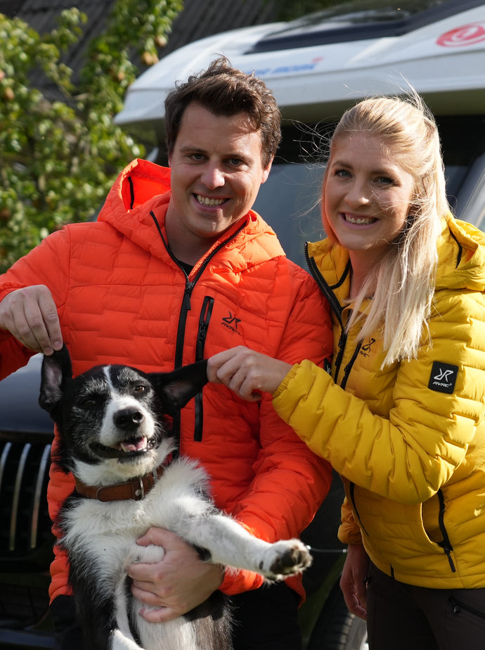 2 adults with a dog in front of a campervan