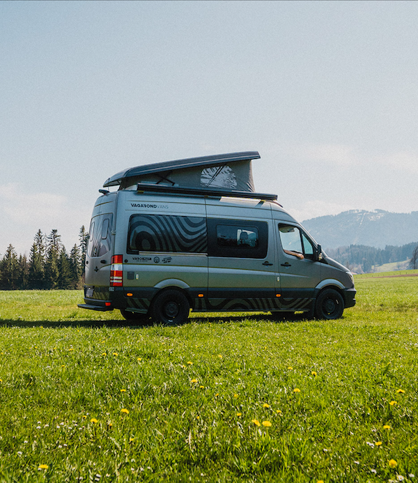 Campervan auf einer Wiese vor den Bergen